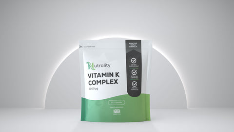 A stand-up pouch of Nutrality Vitamin K Complex dietary supplement, featuring a white upper section, a green lower section, and a black vertical label on the right, set against a minimalist gray background with a soft arch light.